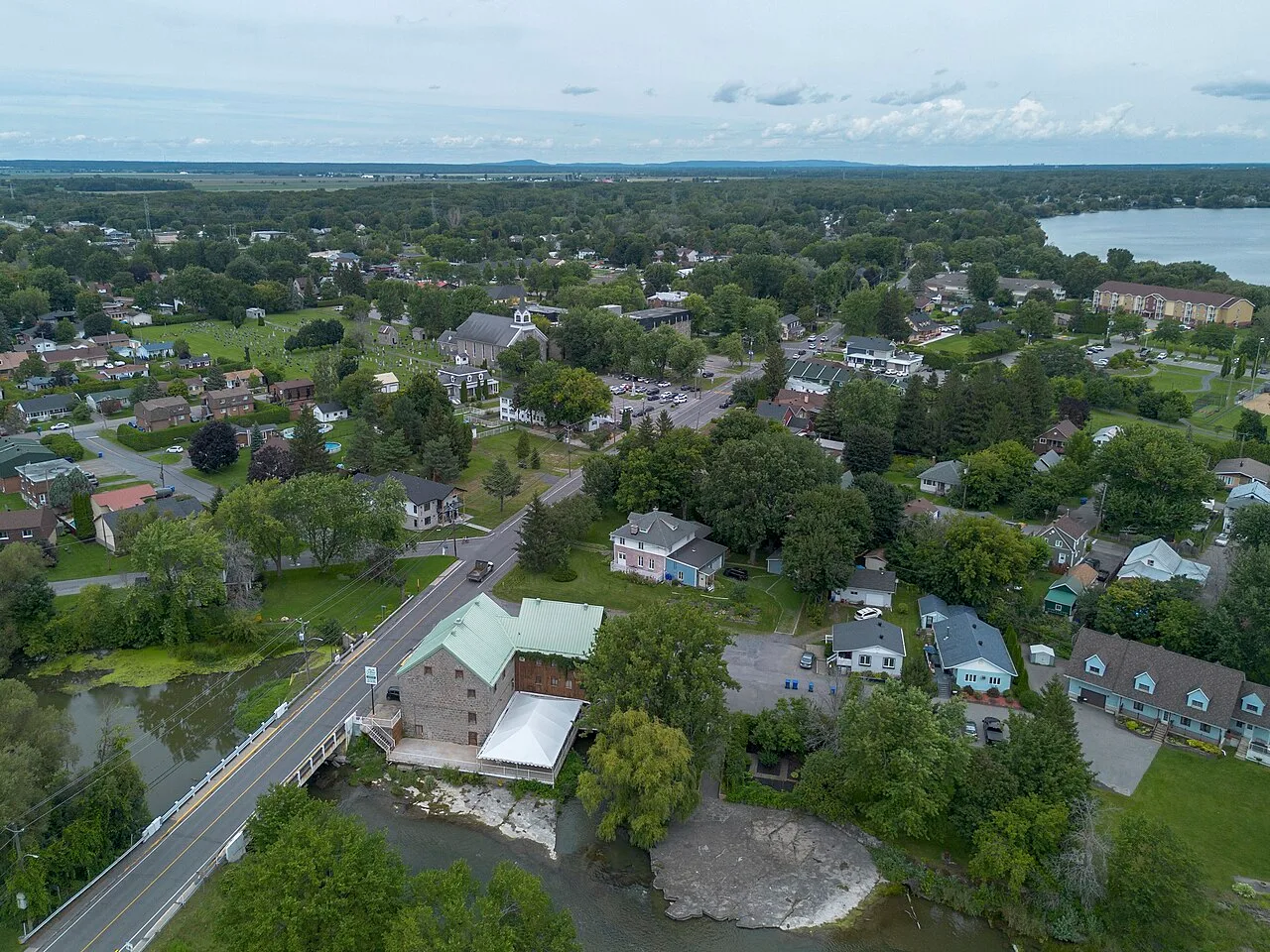 Homes and the historic stone mill of Coteau-du-Lac, Quebec, beside the river rapids with the St. Lawrence in the background